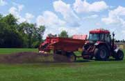 Image of a spreader fertilizing Greely's sports field topdressing soil. Click here to learn more.